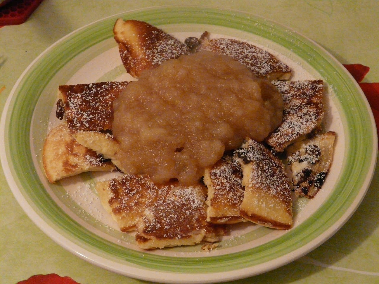 Schlutzkrapfen dorati e croccanti impiattati su un piatto bianco, spolverati di zucchero a velo, con dentro visibile il ripieno di mele e frutta secca leggermente caramellata