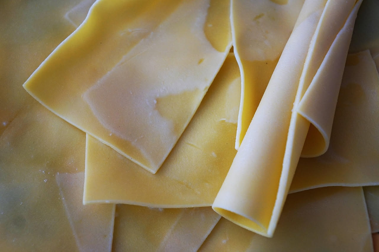 Scrippelle arrotolate di colore dorato in una ciotola di ceramica bianca, immerse in brodo trasparente e fumante, con prezzemolo fresco visibile sulla superficie