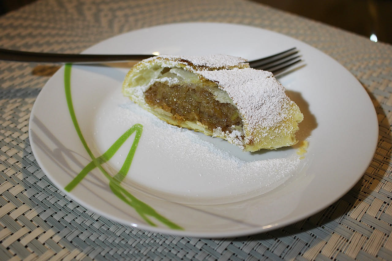 Sfoglia di maiale ripiena dorata in padella, tagliata a metà per mostrare il ripieno di prosciutto, formaggi e erbe aromatiche, contornata da verdure grigliate
