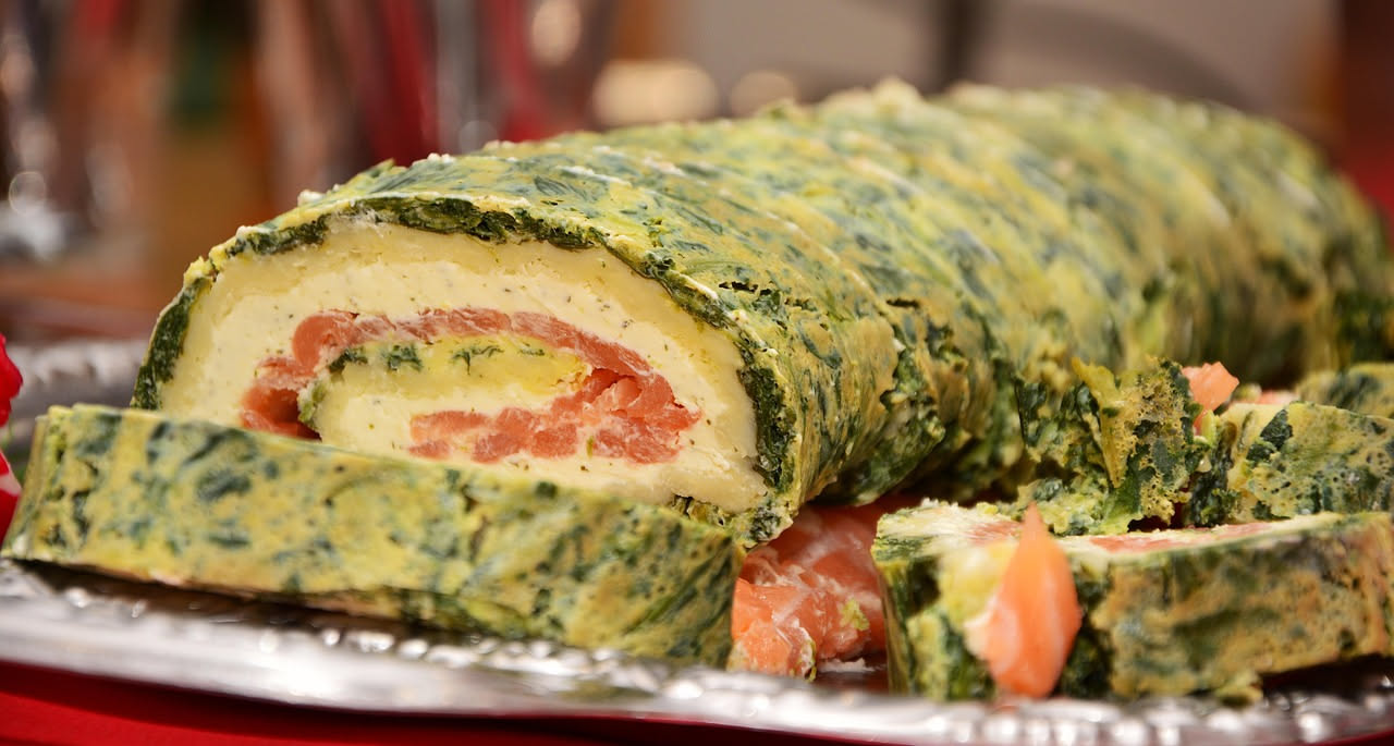 Una sfoglia rettangolare dorata e croccante con verdure verdi e colorate (zucchine, spinaci, peperoni) visibili sulla superficie, servita in un piatto bianco, tagliata in rettangoli