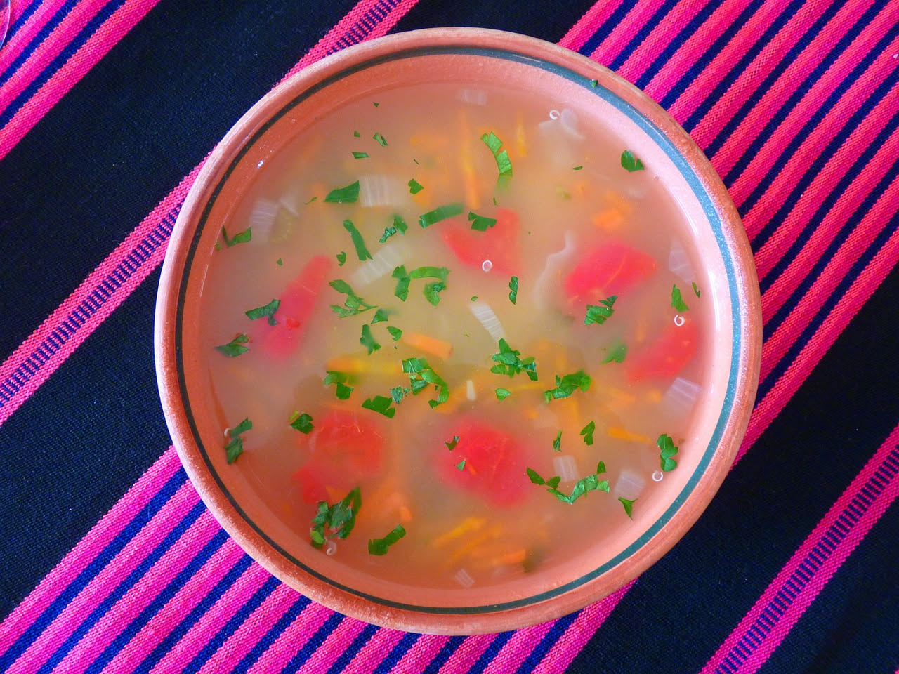 Una ciotola di sopa d'asen con pane inzuppato in brodo di verdure, cavolo e cipolla visibili in primo piano, vapore caldo che sale, servita in stoviglia di ceramica