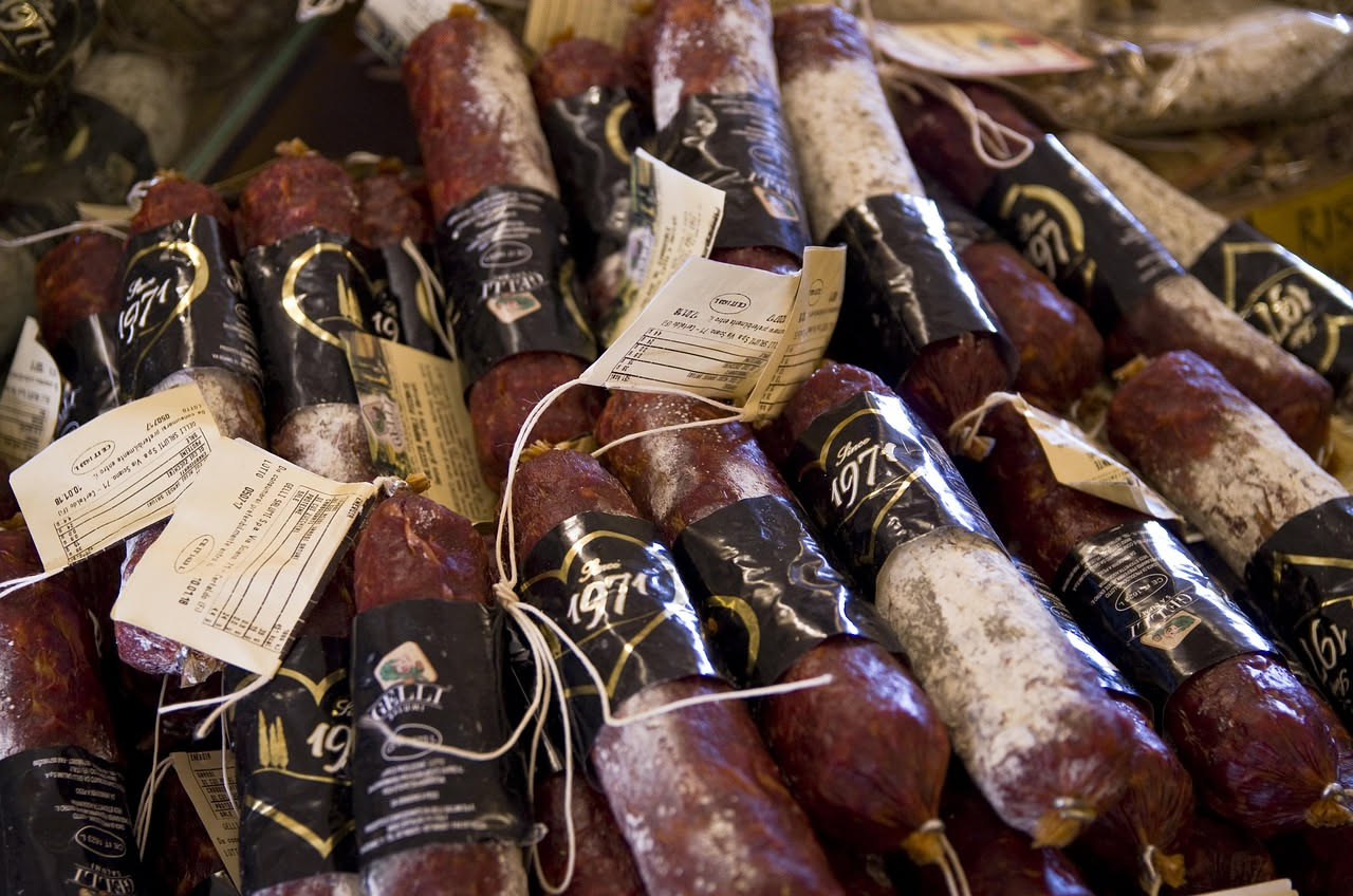 Fette di soppressata irpina tagliate su un tagliere di legno con grani di pepe visibili e colore rosso scuro della pasta