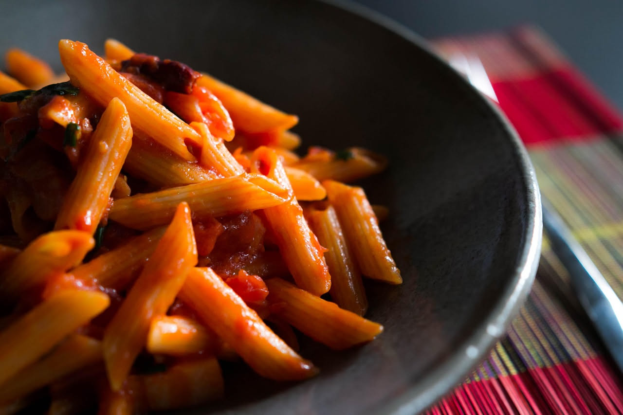 Soppressata molisana affettata su un piatto bianco, mostrando la sezione trasversale con il rosso della carne punteggiato dal pepe nero, buccia scura e leggermente increspata, accompagnata da pane tos