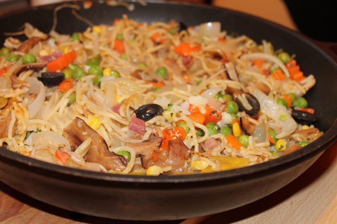 Piatto di spaghetti alla palermitana con sardine intere, finocchio tenero, uvetta dorata e zafferano, conditi in olio aromatico e serviti su un piatto bianco