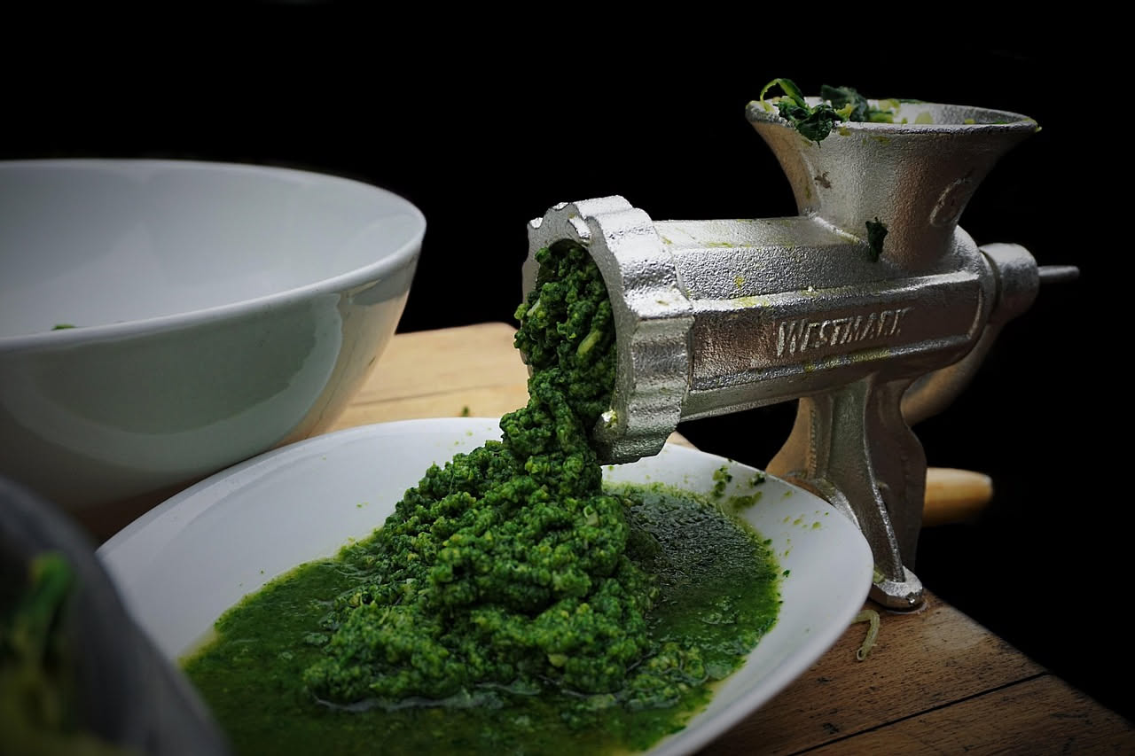 Piatto bianco con spaghetti alle cime di rapa: pasta gialla dorata avvolta intorno a porzioni di verdura verde scuro, condita con olio brillante, aglio dorato e fili di peperoncino rosso, servita su f