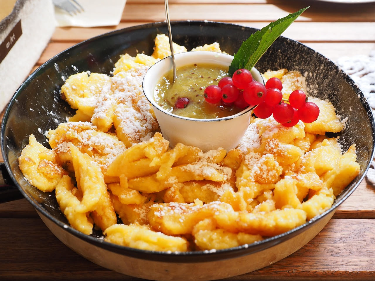 Spatzle toscani dorati in un piatto bianco, conditi con sugo di carne e parmigiano grattugiato, guarniti con prezzemolo fresco