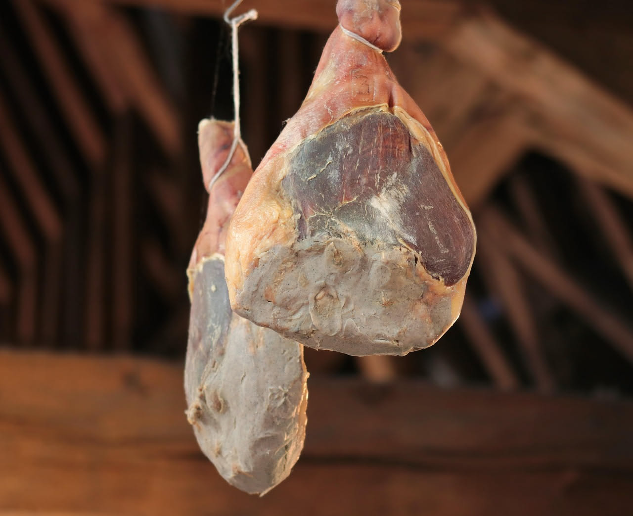 Fette di speck irpino affumicato color mogano su un tagliere di legno, con la superficie lucida e le venature di grasso distribuite uniformemente