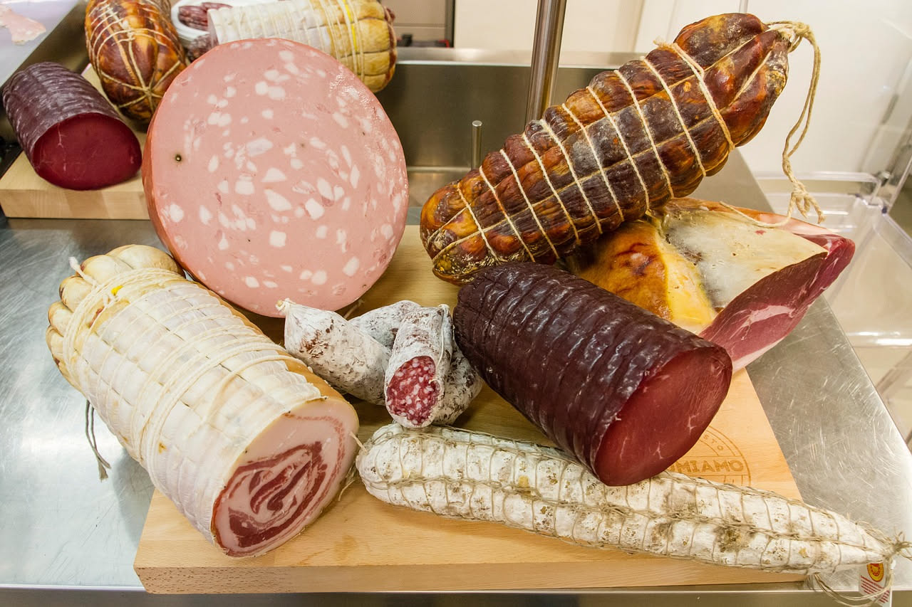 Spianata affettata su un tagliere di legno, con pepe visibile sulla superficie, accanto a un coltello e pane tostato