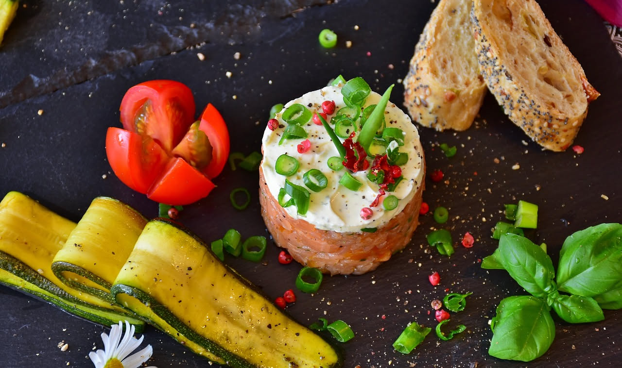 Fetta di stracchino affumicato color crema con sfumature più scure sulla crosta, servita su un piatto bianco con pane tostato accanto e foglie di rucola fresca