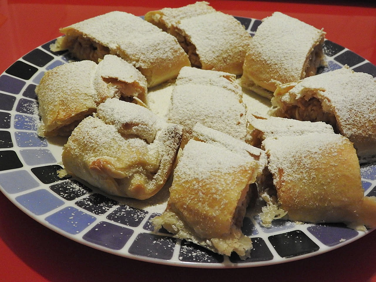 Strudel salato di cavolo tagliato a fette su un piatto bianco, sfoglia dorata e croccante con ripieno di cavolo verde visibile, guarnito con semi di sesamo
