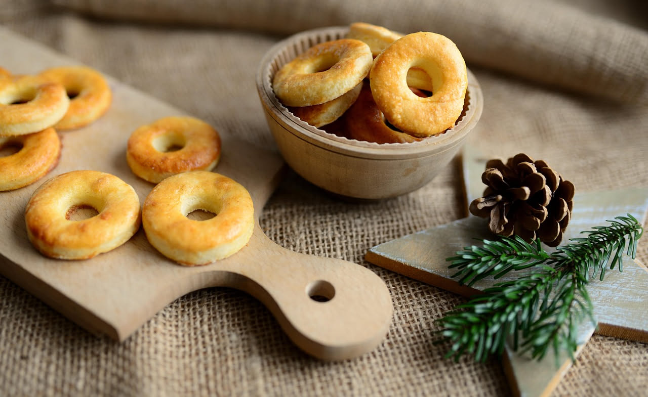 Taralli al finocchio dorati e croccanti disposti su un piatto di ceramica bianca, con semi di finocchio visibili sulla superficie