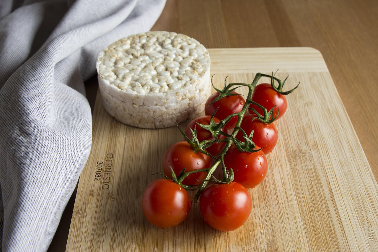 Tre tartine di pane tostato ricoperte di burrata bianca cremosa e fettine di pomodoro rosso maturo, decorate con foglie di basilico fresco verde, appoggiate su un piatto bianco