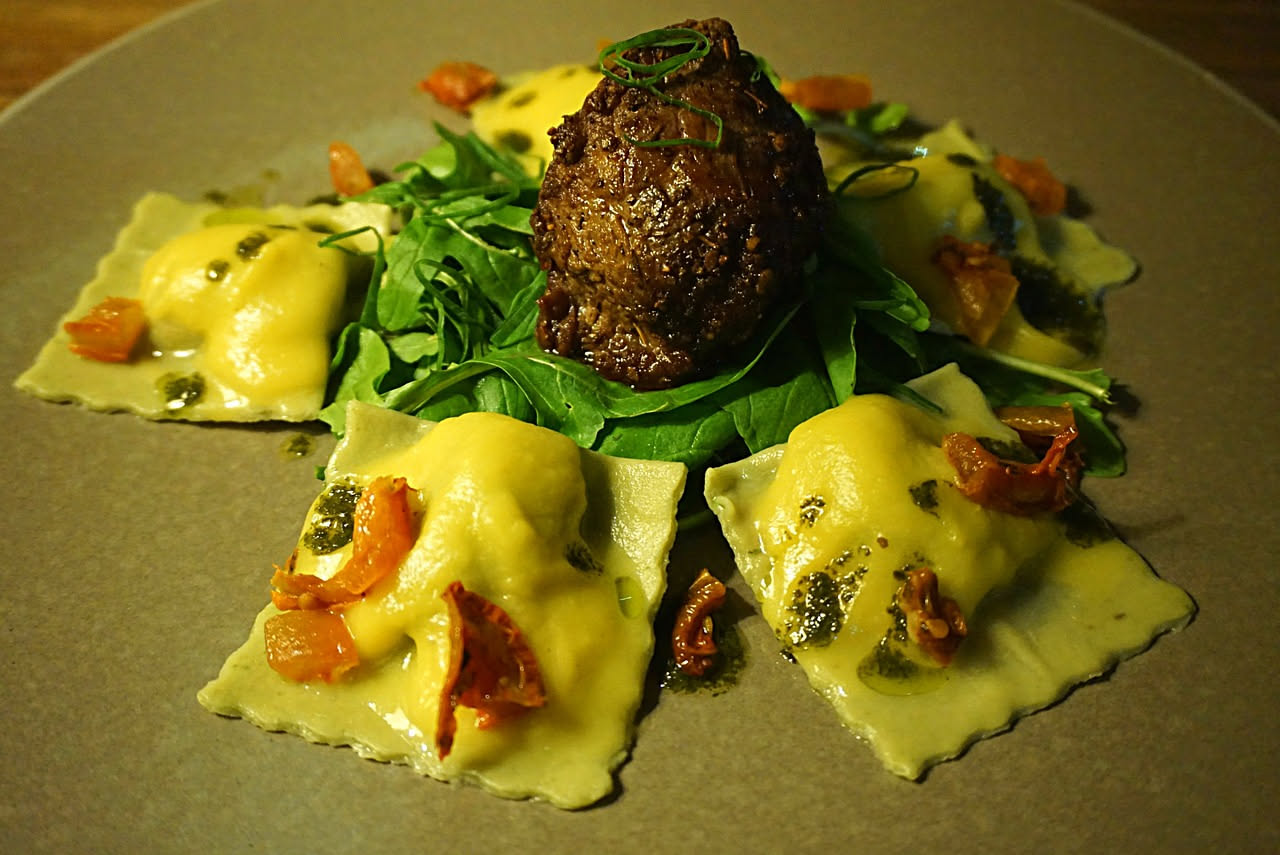 Tartufi di varie misure color marrone scuro e grigio chiaro immersi in liquido trasparente leggermente ambrato, con spezie visibili, in vasetto di vetro da cucina