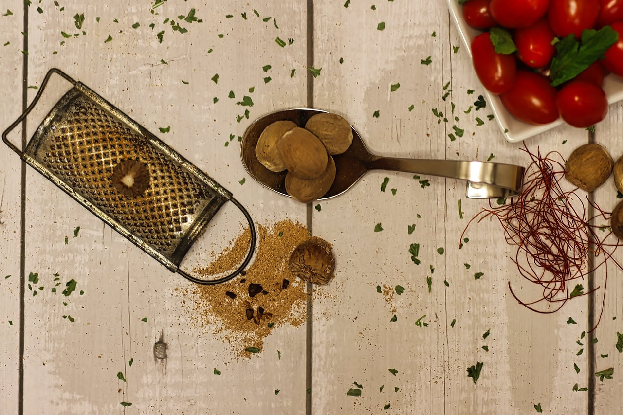 Tartufo nero intero accanto a una grattugia microplane con scaglie di tartufo nero appena grattugiate sparse su un piatto bianco, con il tartufo parzialmente grattugiato sullo sfondo