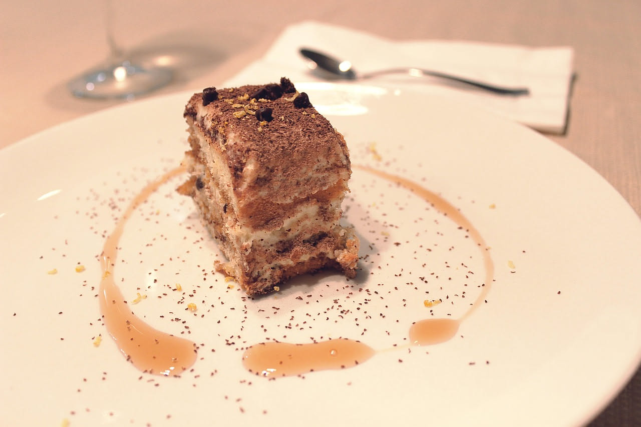 Crostini color dorato con tartufo nero grattugiato sopra, serviti in piatto bianco, con fette di tartufo fresco accanto e un coltellino da tartufo