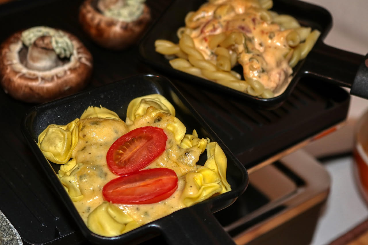 Tordelli di carne appena cotti nel piatto, di forma ovale, ricoperti di sugo rosso, guarniti con parmigiano grattugiato e prezzemolo fresco, vapore ancora visibile