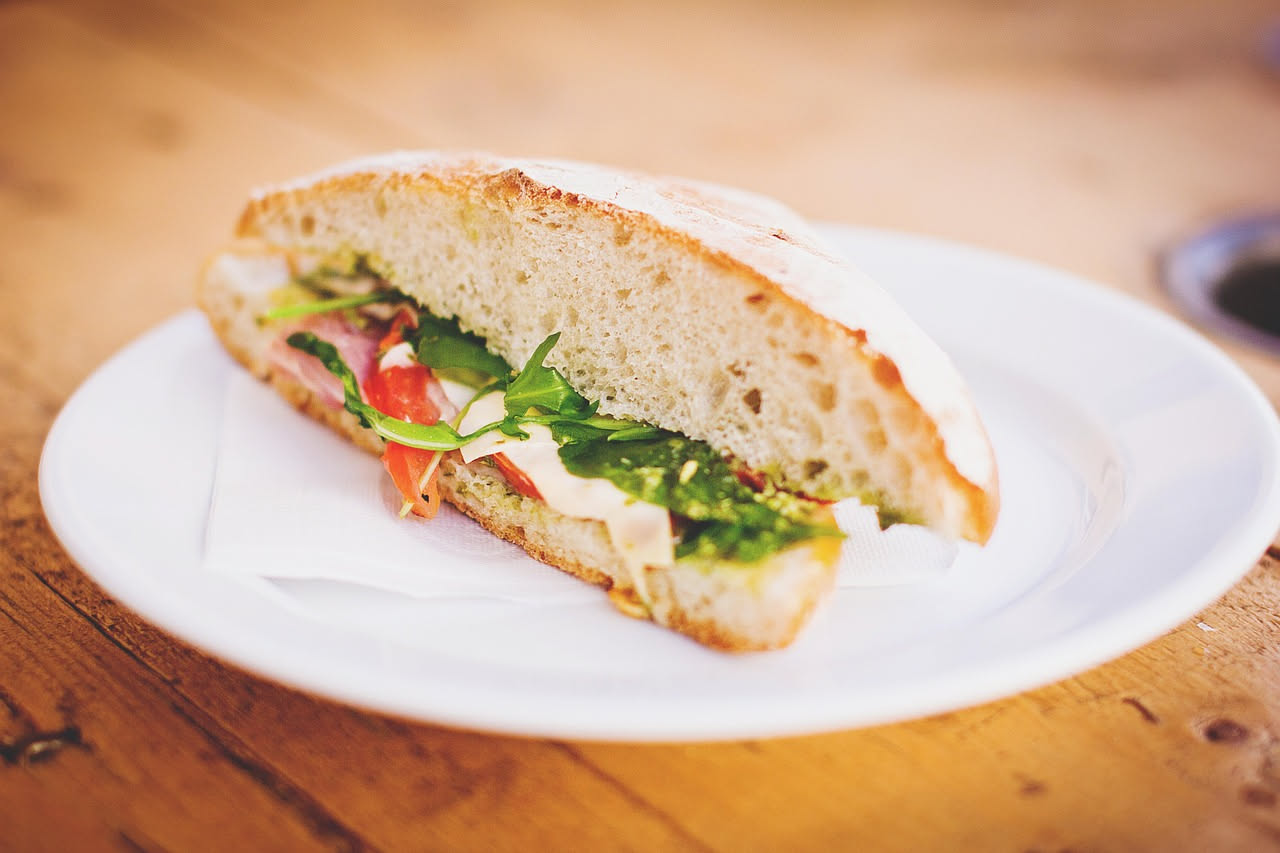 Torta al testo salata dorata su una piastra di ferro rovente, con sfoglie sottili e leggermente abbrustolite, accanto a un piatto di formaggi bianchi