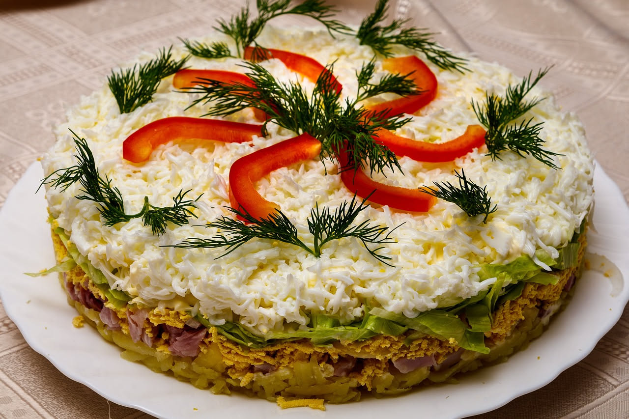 Torta di riso salata dorata in un piatto bianco, tagliata in spicchi, con la sezione interna che mostra il riso amalgamato al formaggio e al ragù, contorno di insalata verde fresca