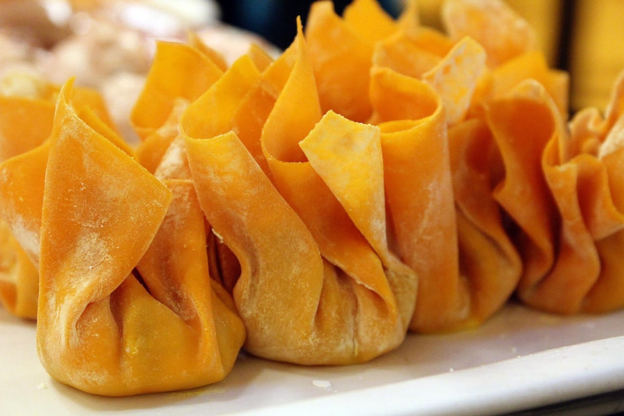 Tortellacci di zucca fatti in casa, serviti in un piatto fondo di ceramica bianca con brodo vegetale caldo, guarniti con una noce di burro fuso, formaggio grattugiato e una foglia di salvia fresca. La