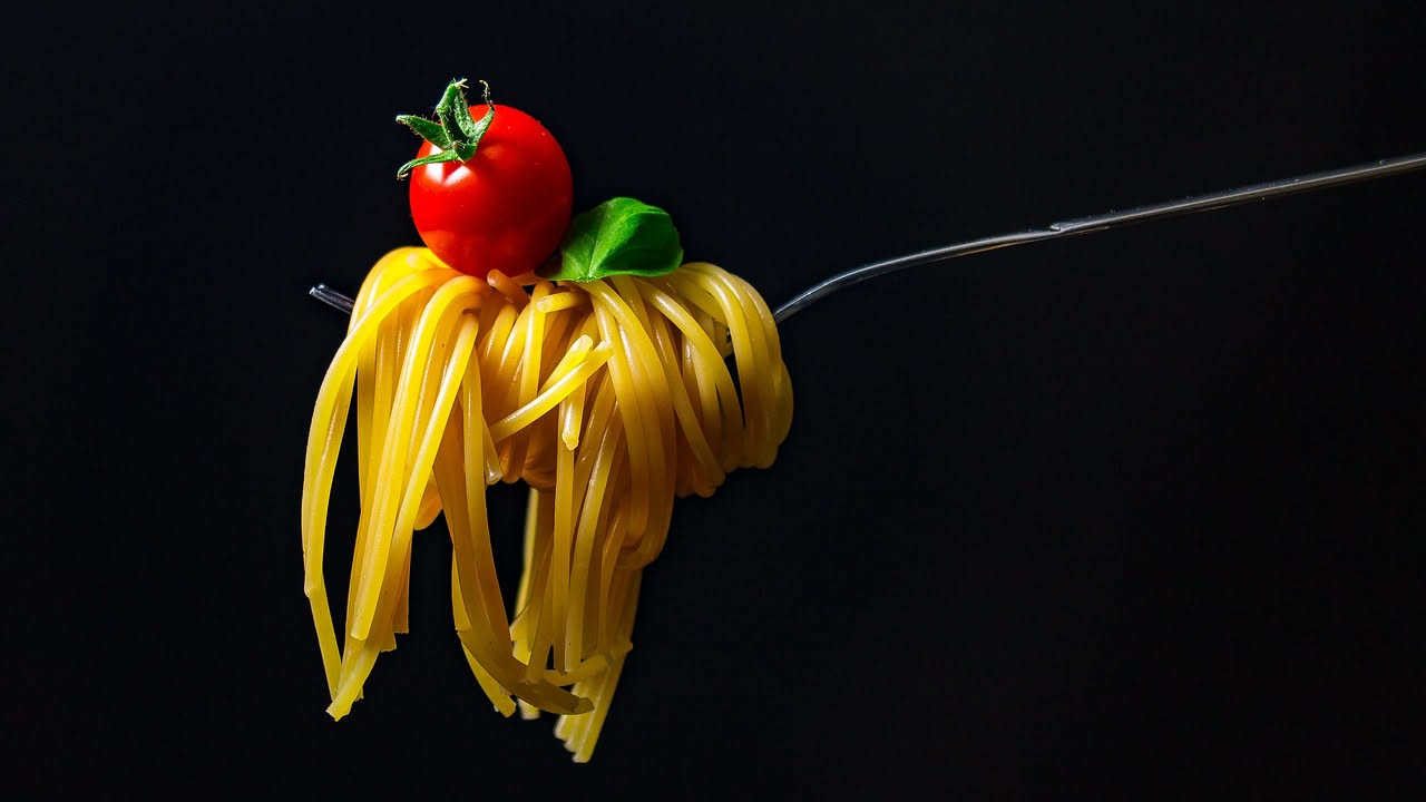 Vermicelli al forno in una pirofila di ceramica bianca, croccanti e dorati in superficie con bordi caramellati, formaggio fuso visibile, al naturale senza contorno