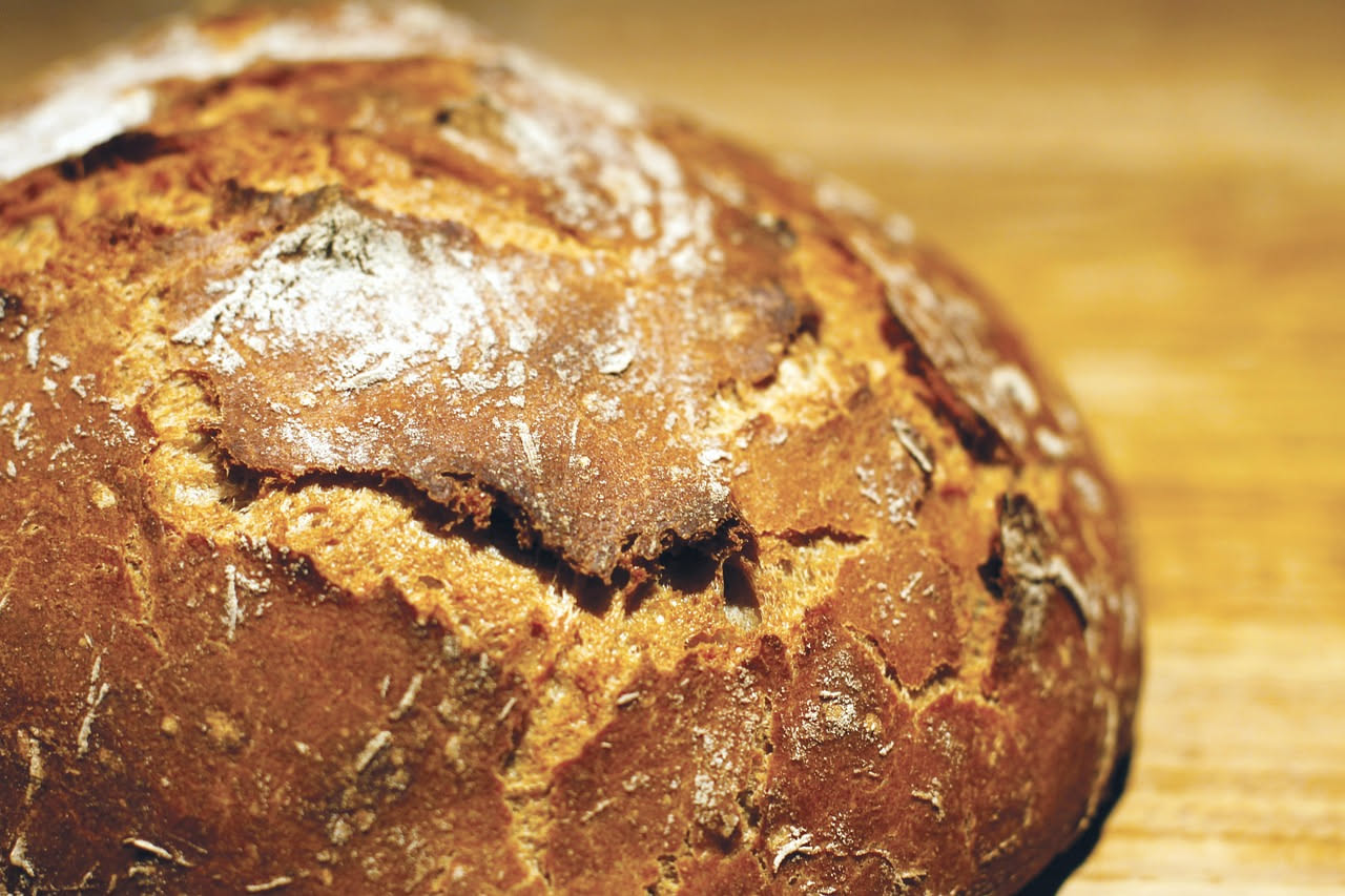 Una ciotola di zuppa di pane raffermo con fette di pane tostato galleggianti in brodo marrone, accompagnate da verdure morbide come carote e sedano, condita con olio verde oliva e prezzemolo fresco