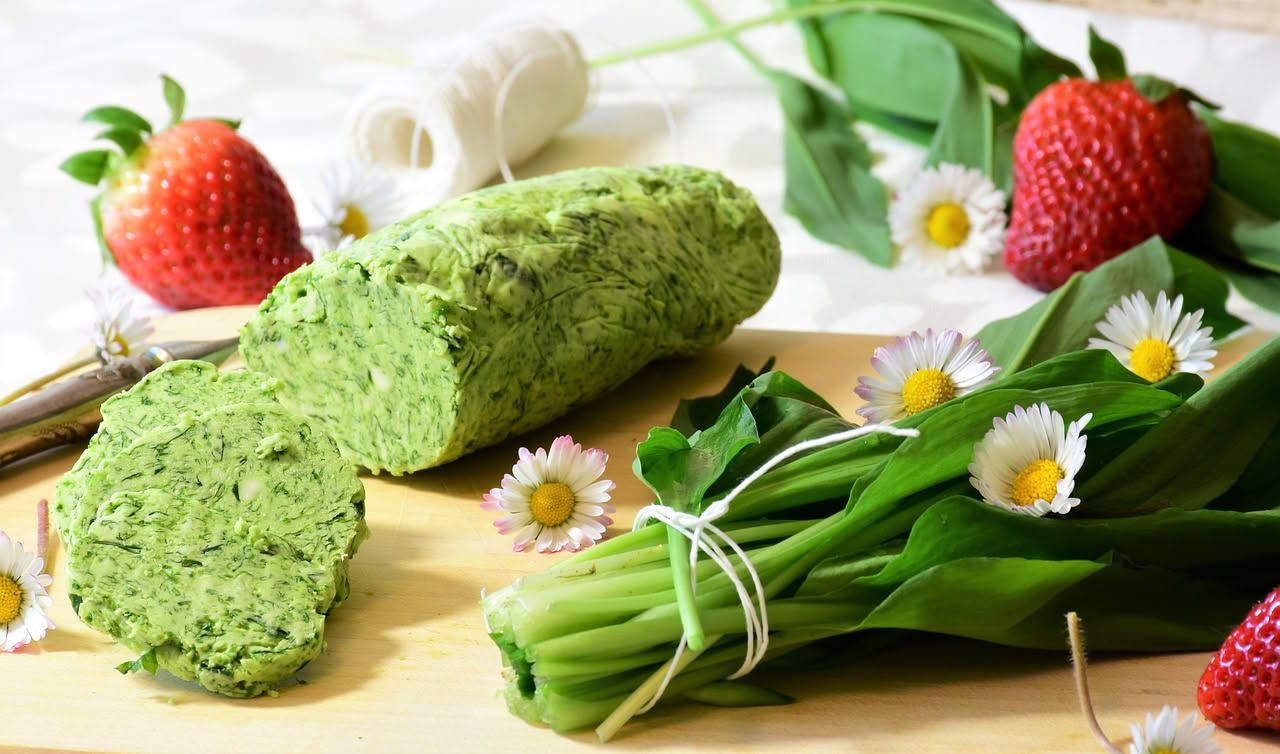 Frittata dorata e gonfia in padella di ferro con erbe selvatiche verdi tagliate a pezzi, uova cotte, formaggio grattugiato e prezzemolo fresco